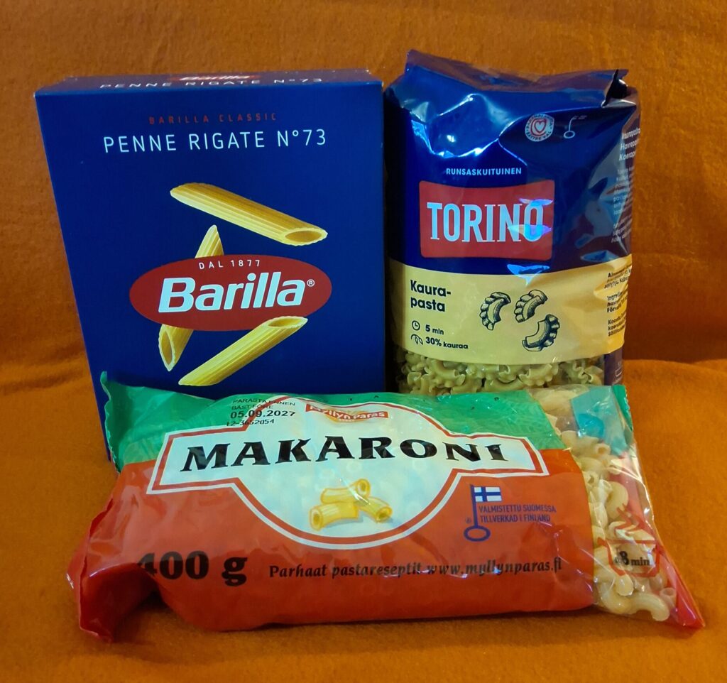 Kolme erilaista makaroni- tai pastapakkausta, joista yksi on kartonkia ja kaksi muovia.